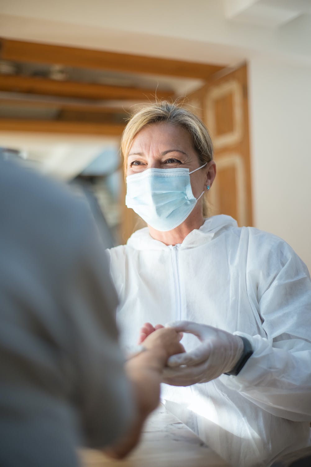 masked medical staff smiling holding a patient's hands