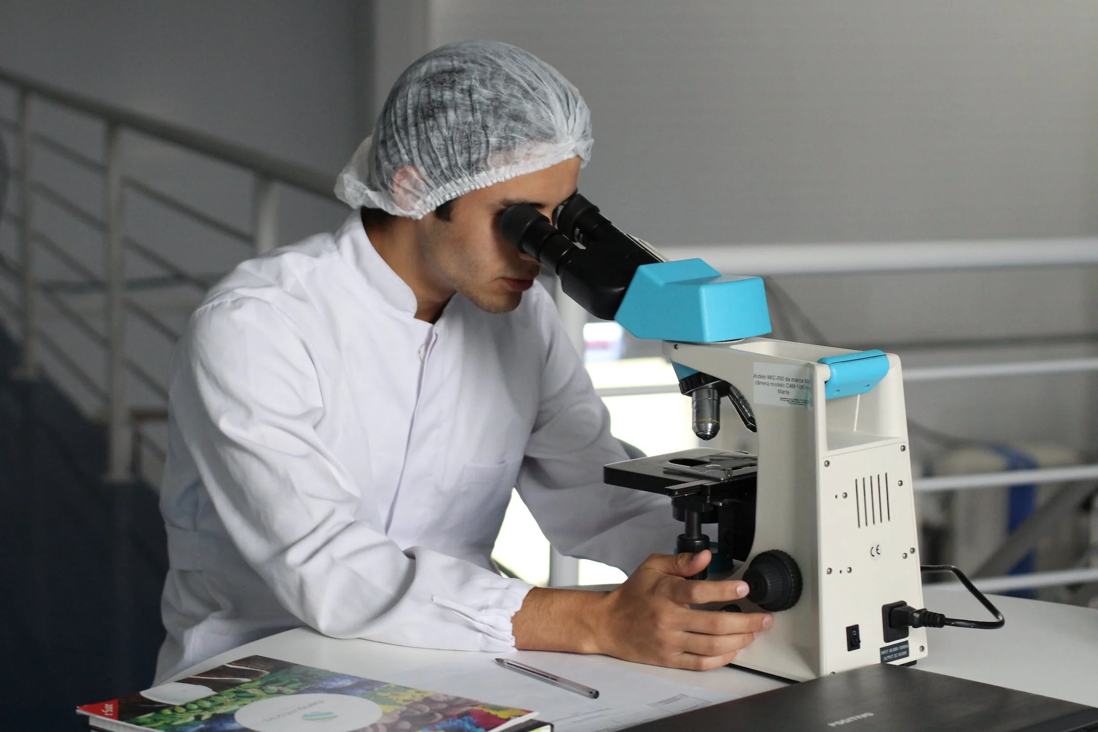 Man in lab uniform looking through microscope